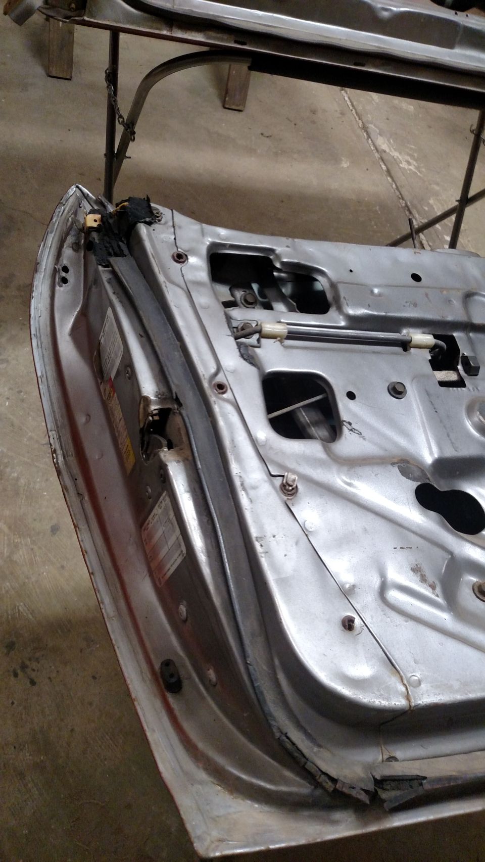 Interior of a silver car door, showing internal mechanisms and some labels