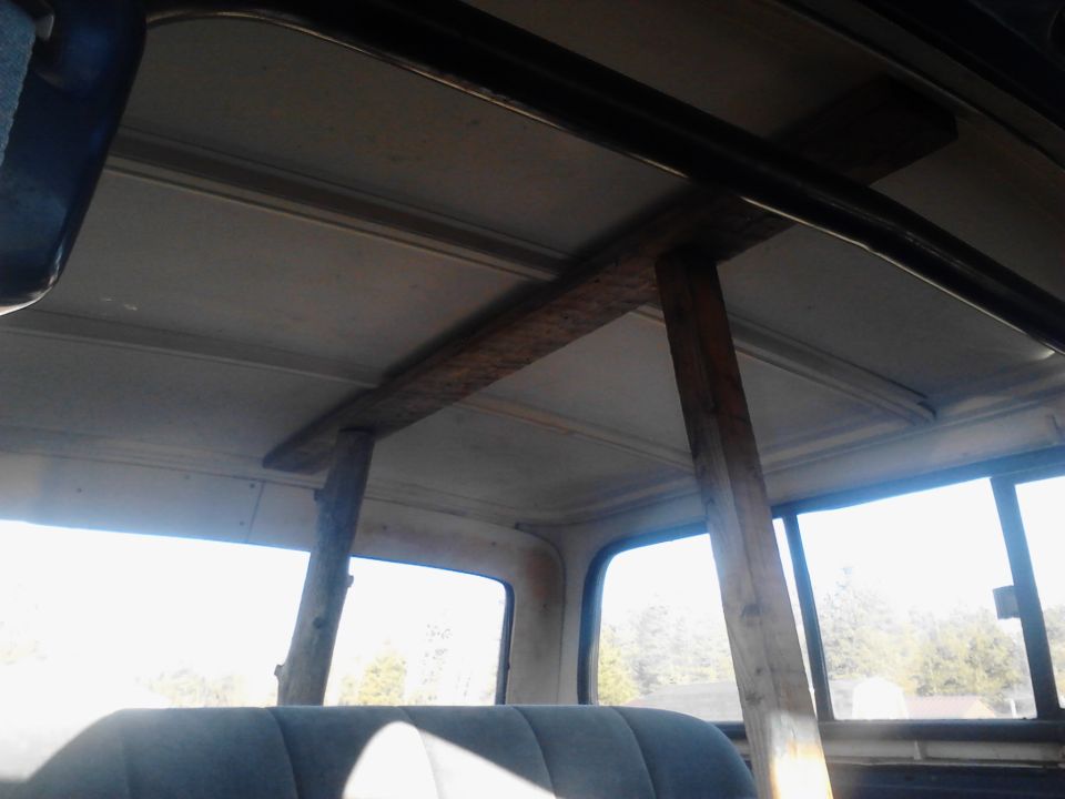 Interior view of a vehicle with crude wooden beams supporting the roof