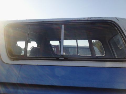 1978 Ford Bronco - View through the side window of a blue and white vehicle, with another vehicle visible in the background.
