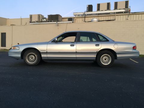 1994 Ford Crown Victoria - A silver sedan, likely a 1995 Ford Crown Victoria, is viewed from the side in a parking lot.