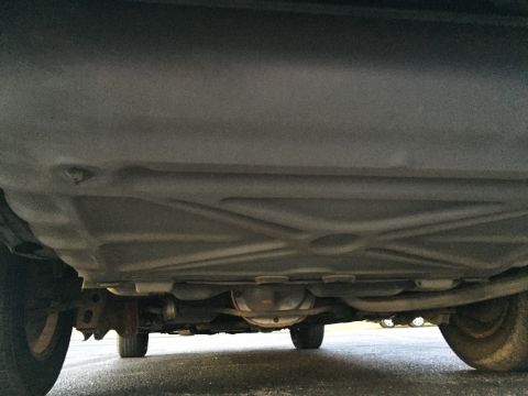 1994 Ford Crown Victoria - The underside of a car is shown, revealing the fuel tank and drivetrain components.