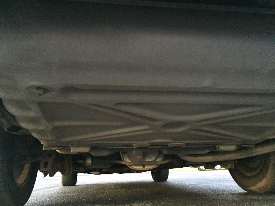 Underside view of a car, showing the fuel tank and rear differential. Tires visible