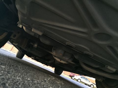 1994 Ford Crown Victoria - The underside of a vehicle is captured from a low angle, revealing mechanical components and a glimpse of another car.