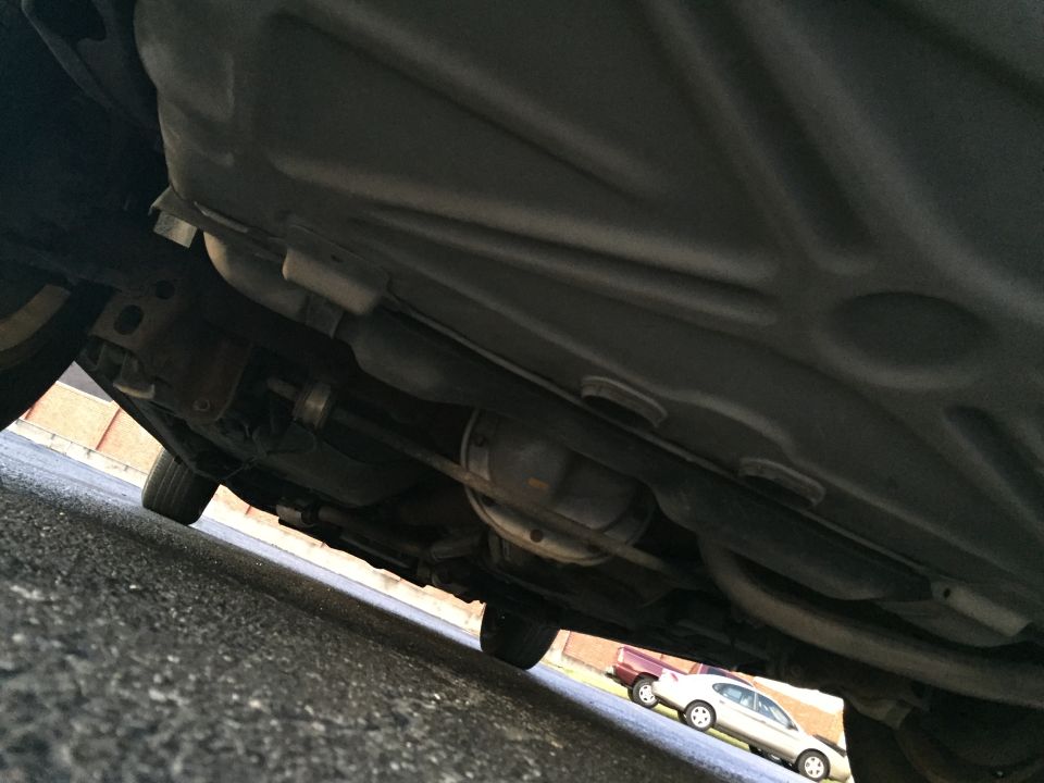 Underside of a car showing exhaust and differential, with another car visible in the background