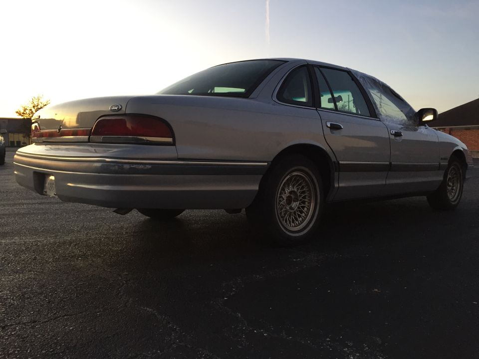 1994 Ford Crown Victoria sedan, rear 3/4 view, silver paint, aftermarket wheels