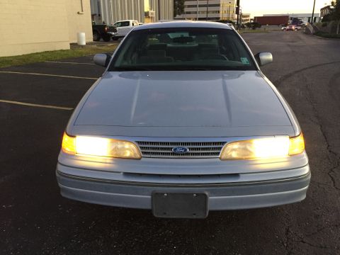 1994 Ford Crown Victoria - The front of a 1994 Ford Crown Victoria is shown with its headlights on.