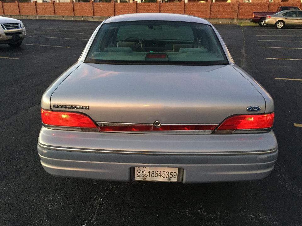 Silver sedan rear view, showing taillights, license plate, and "Crown Victoria" badging
