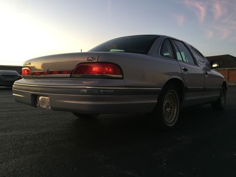 1994 Ford Crown Victoria - Rear view of a silver 1994 Ford Crown Victoria sedan. Another vehicle is visible in the background.