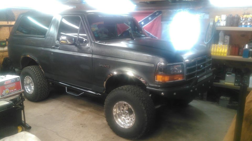 Lifted dark gray Ford Bronco with polished wheels parked in a lit garage