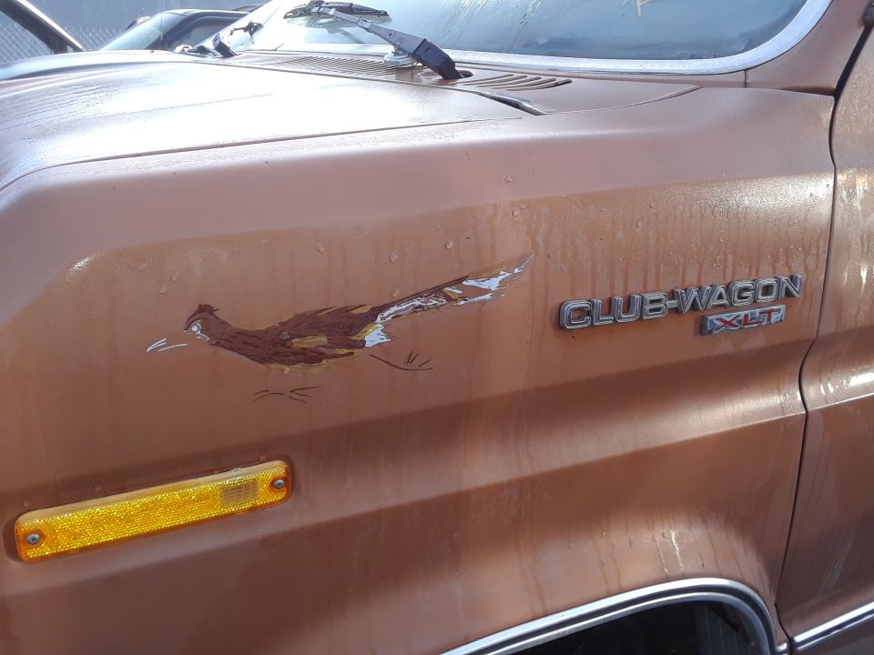 Brown van side view with roadrunner decal and "CLUB WAGON XLT" badge