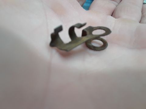 1994 Ford Bronco - A close-up of a single, corroded metal clip with a distinctive shape, resting on a hand.