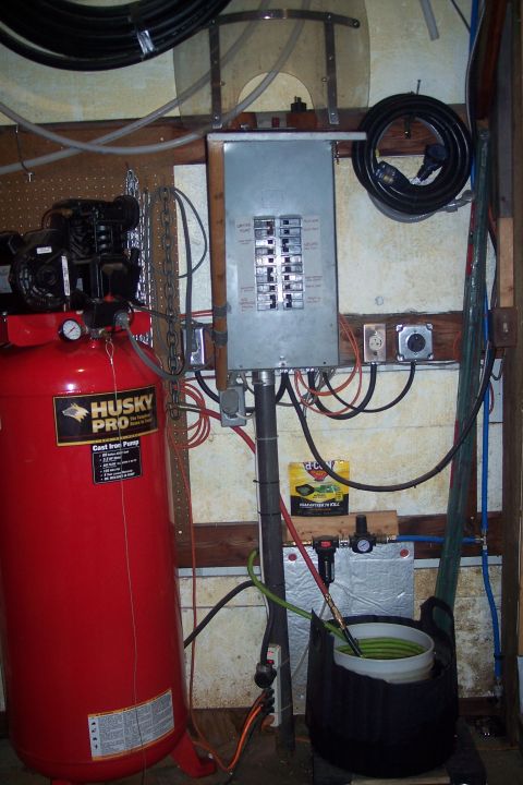 1995 Ford Bronco - A workshop scene an air compressor, electrical panel, and various hoses and cords.