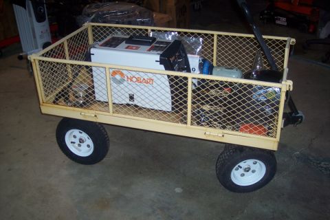 1995 Ford Bronco - A utility cart is loaded with a Hobart welder and other items, parked indoors.