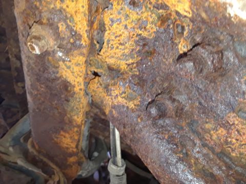 1994 Ford Bronco - The underside of a vehicle shows extensive rust damage on its frame components.