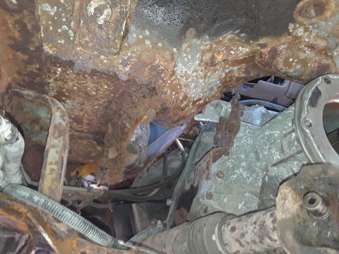 1994 Ford Bronco - Undercarriage of a severely rusted vehicle, showing extensive corrosion and mechanical parts.