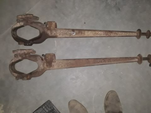 1994 Ford Bronco - Two rusty metal suspension control arms are displayed against a concrete floor.
