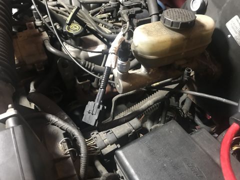 1994 Ford Bronco - Close-up view of an engine compartment, showing the brake fluid reservoir and various electrical connections.