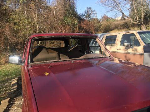 1994 Ford Bronco - Front view of a red 1994 Ford Bronco missing its windshield, with another vehicle behind it.