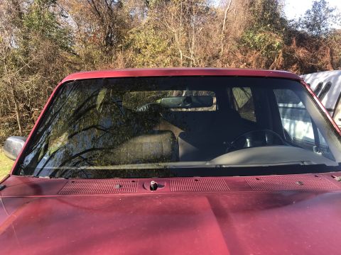 1994 Ford Bronco - Interior view of a red SUV, showing the dashboard, steering wheel, and seats through the windshield.