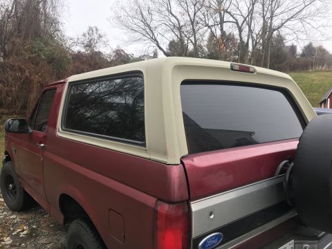 1994 Ford Bronco - Rear view of a 1994 Ford Bronco, showing the passenger side quarter panel and spare tire carrier.