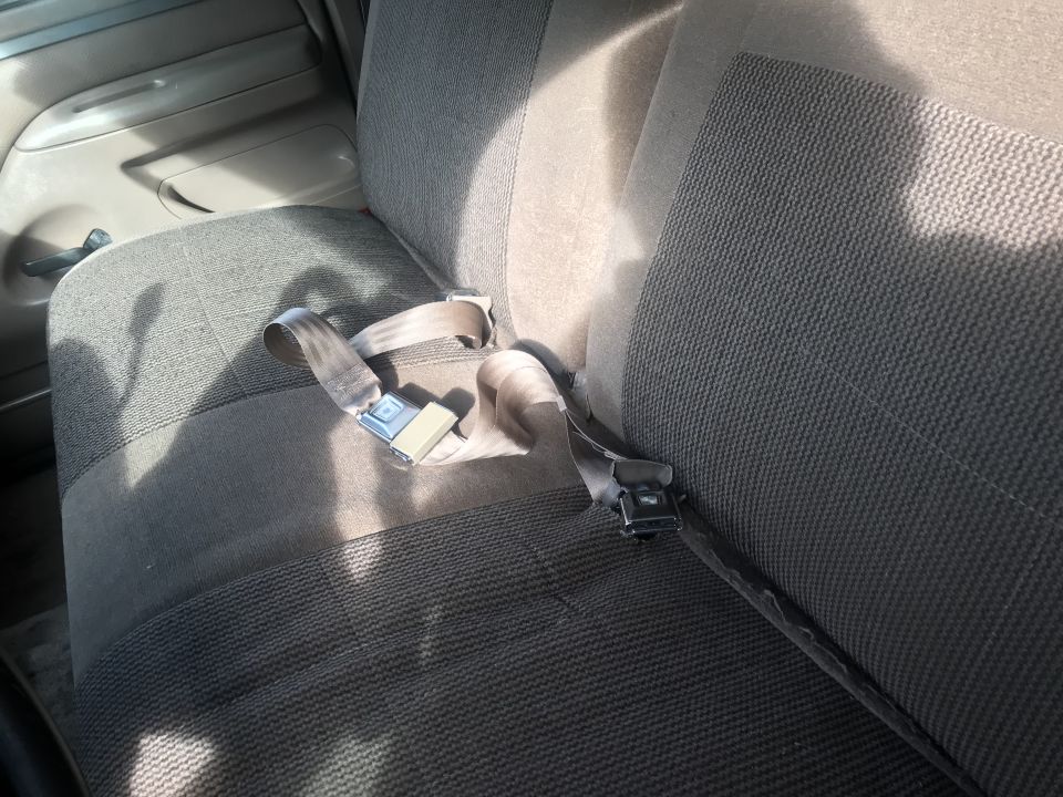 Gray fabric car seats with beige seatbelts and black buckles