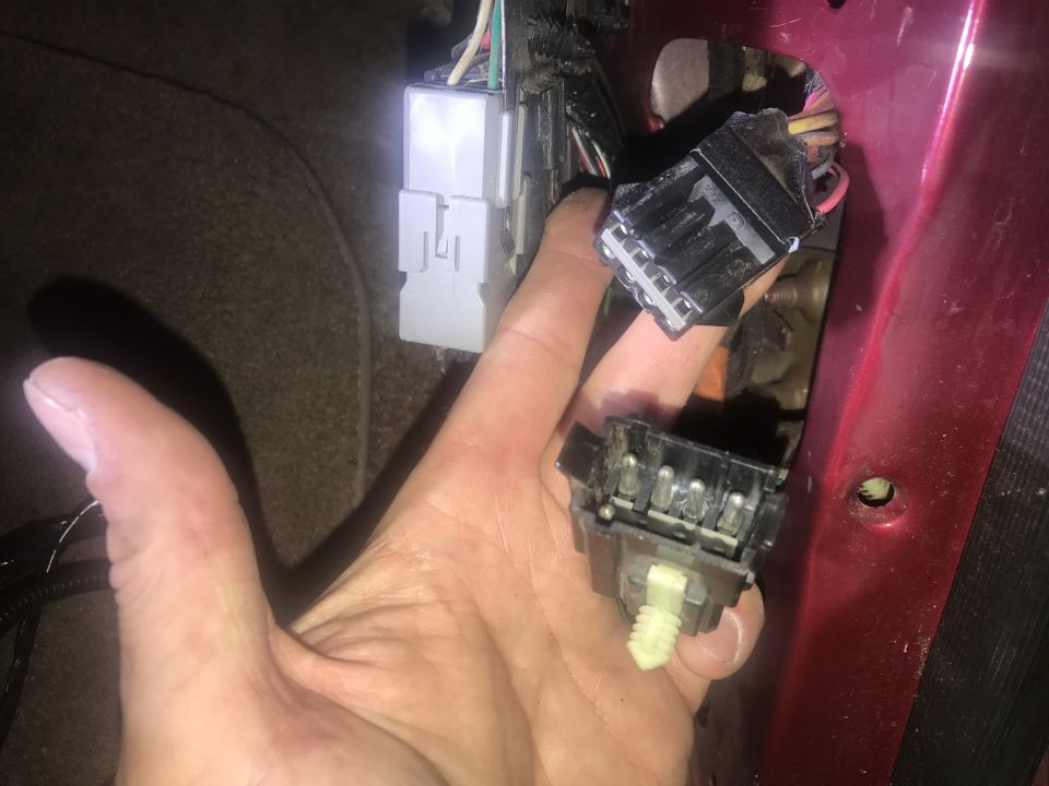 Wiring harness connectors being held, with a Supermotors logo visible