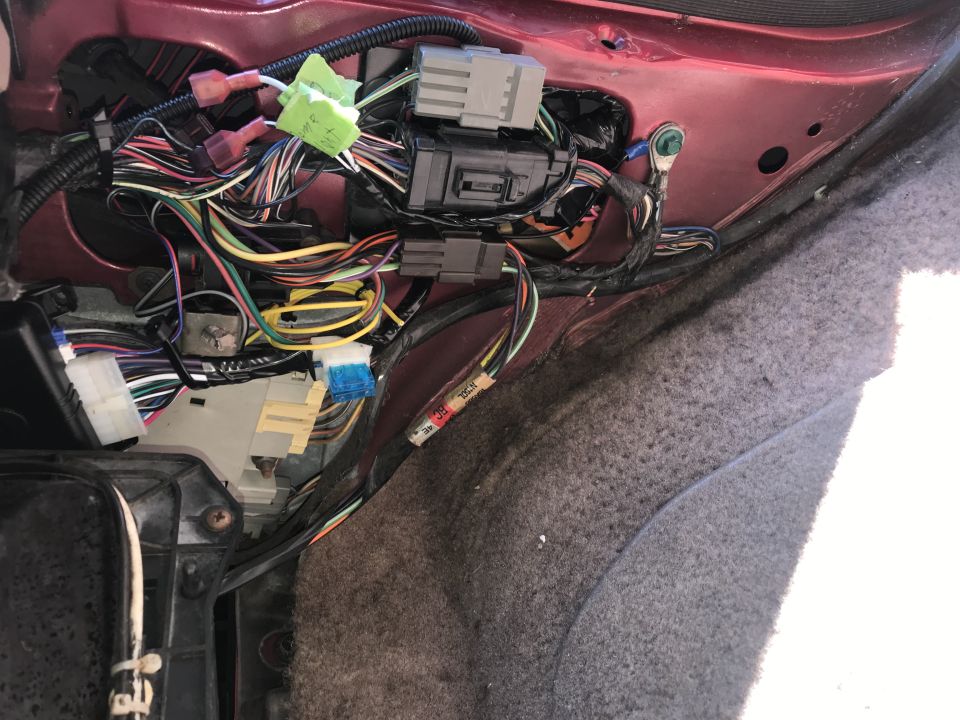 Vehicle wiring harness with many colorful wires and connectors, some taped