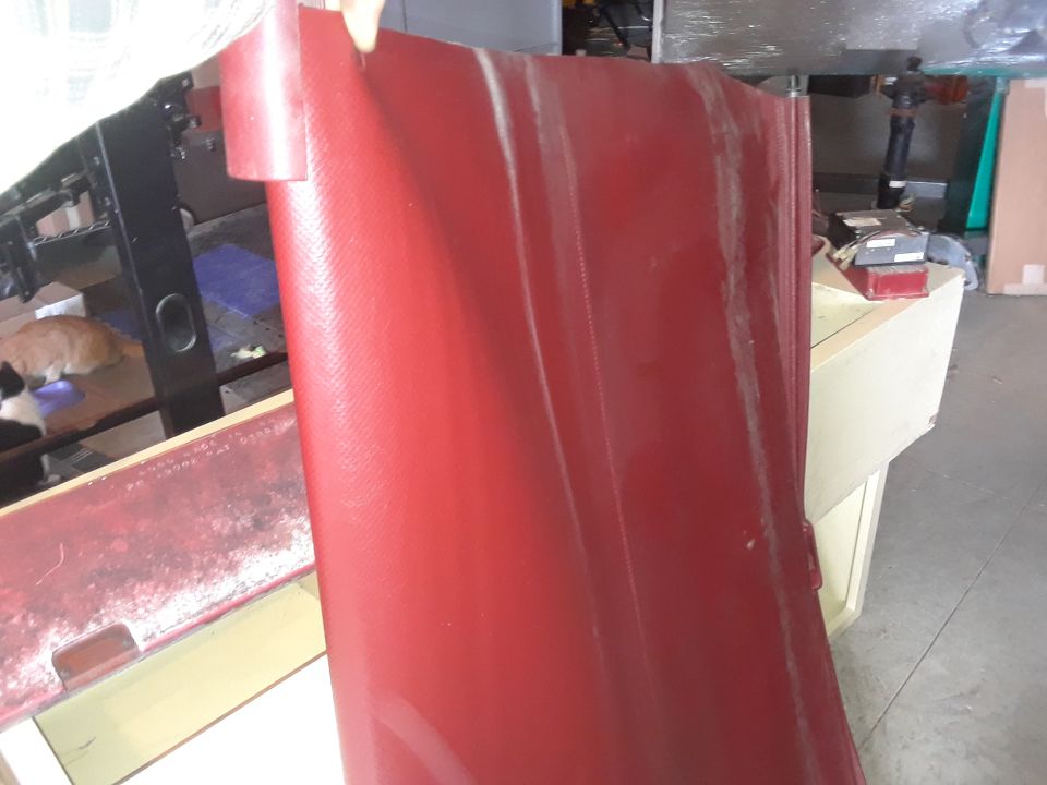red textured panel held up, with a workbench and cats in background