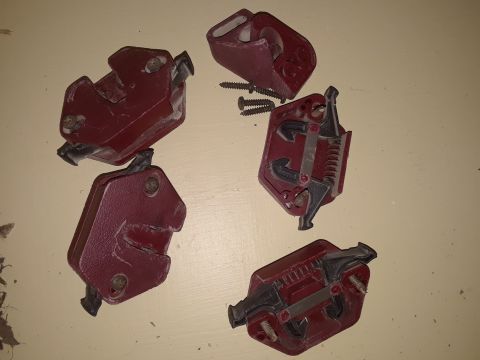 1994 Ford Bronco - Several red door latches and screws are laid out on a flat surface.