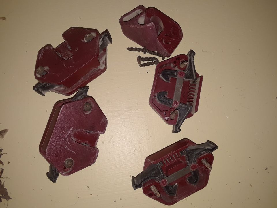 Four red door latches with screws on a light-colored surface