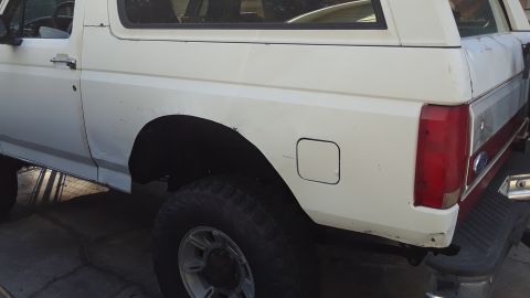 1994 Ford Bronco - Rear view of a white 1994 Ford Bronco, showing the quarter panel, taillight, and a silver stripe detail.