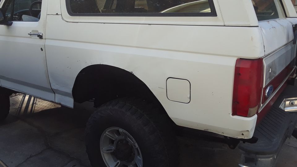 White 1994 Ford Bronco rear quarter panel with red taillight and silver stripe