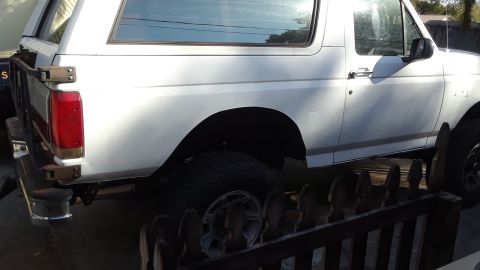 1994 Ford Bronco - This white SUV is seen from the side, with a spare tire and rear rack visible.