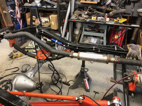1992 Jeep Wrangler - A vehicle's exhaust system, including a muffler and piping, is shown supported by jack stands in a workshop setting.