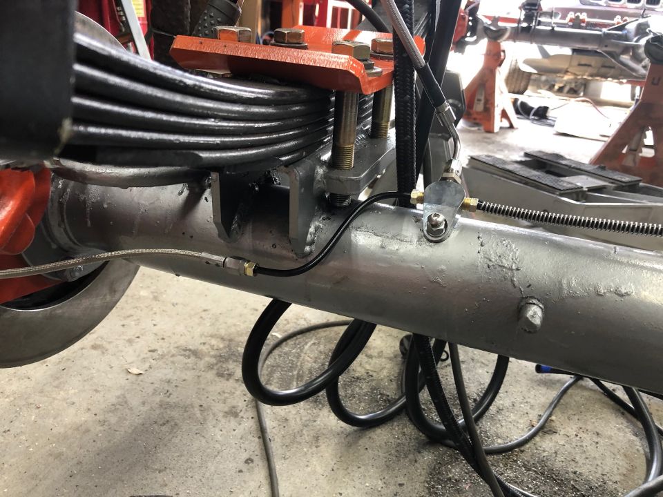 Rear axle assembly with leaf springs, brake lines, and orange suspension components