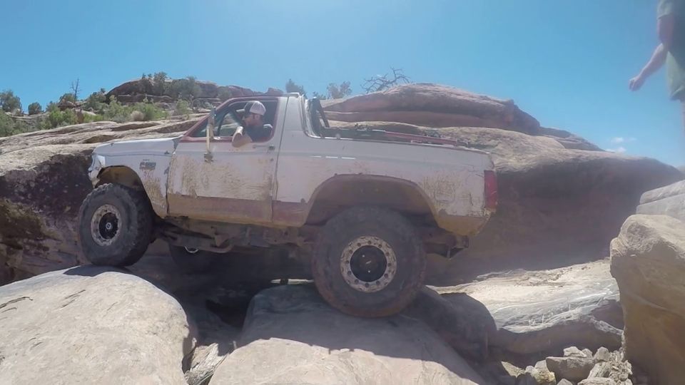 White Ford Bronco navigating rocky terrain, driver visible