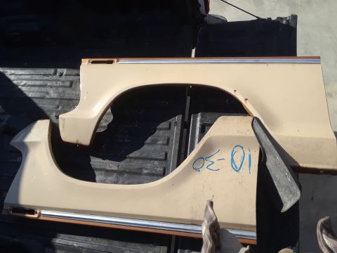 1994 Ford Bronco - Two tan fender pieces, likely for a truck or SUV, are laid out on a dark surface.