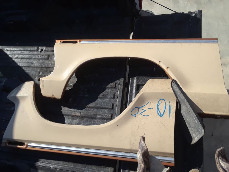 Tan vehicle fender sections with chrome trim and blue writing on one part