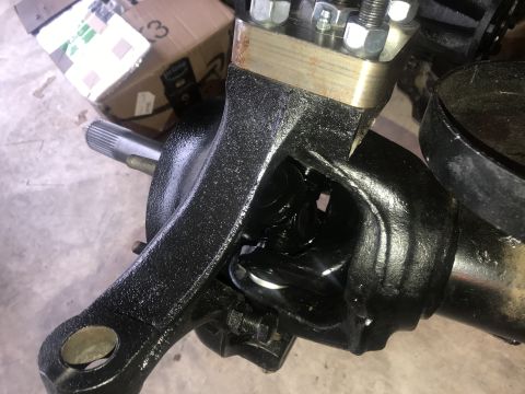 1989 Ford Bronco - A close-up view of a black painted automotive steering knuckle assembly with a splined shaft extending from the left. The assembly shows in…