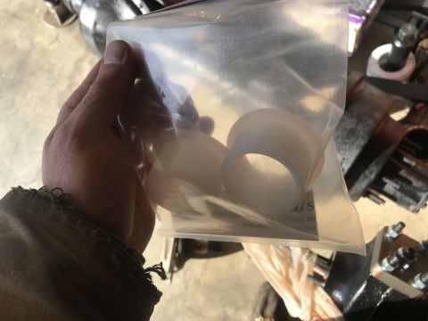 1989 Ford Bronco - A hand holds a clear plastic bag containing white, cylindrical bushings. The bushings appear to be made of a translucent, flexible material.