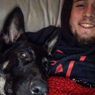 1979 Ford Ranchero - A young man with a beard smiles for a selfie while lying down with a black German Shepherd dog.