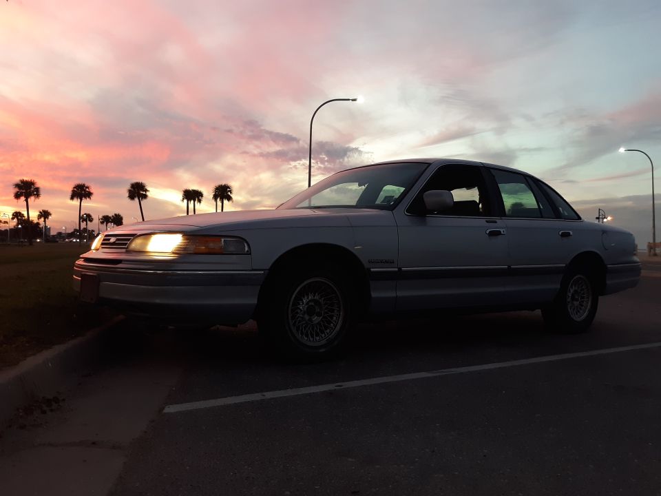 Silver sedan parked at sunset with palm trees.