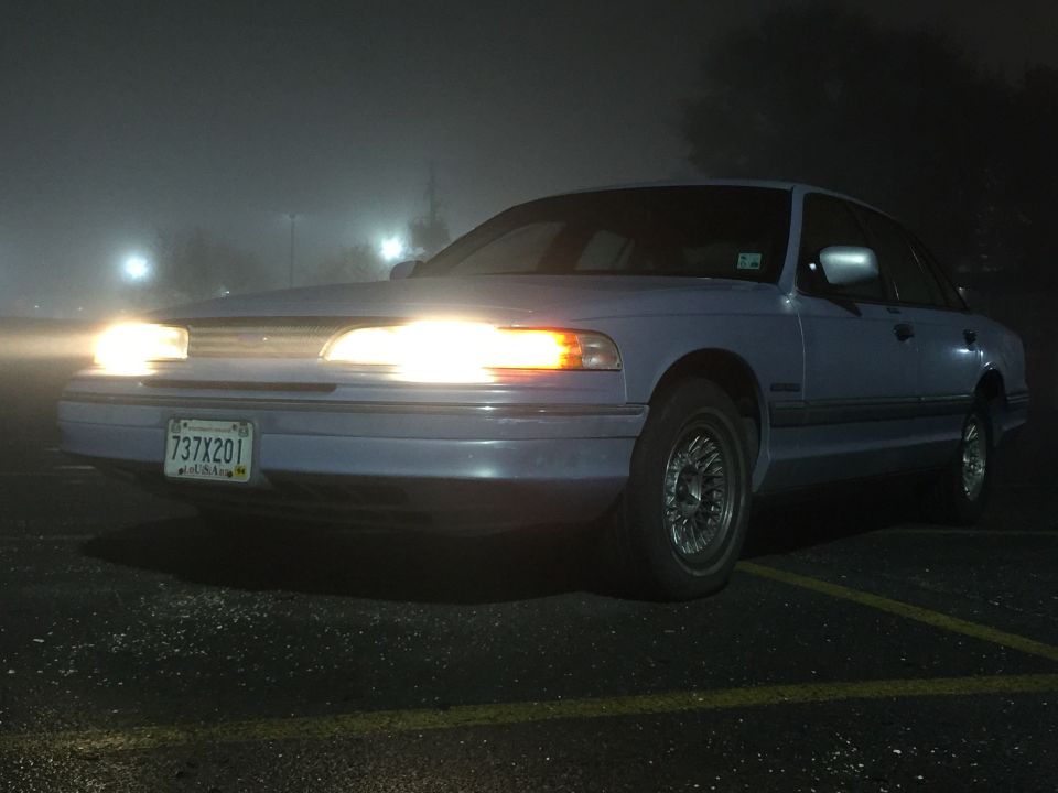 1994 Ford Crown Victoria parked at night with headlights on in fog.