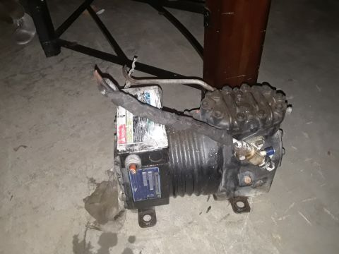 1994 Ford Bronco - A black compressor unit with various labels and wiring is shown on a concrete floor.