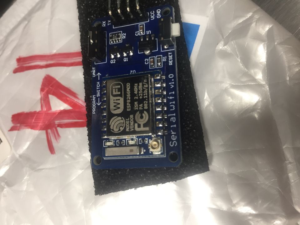 Blue circuit board with "Serial wifi v1.0" and "ESP8266MOD" text, with red markings on white surface.