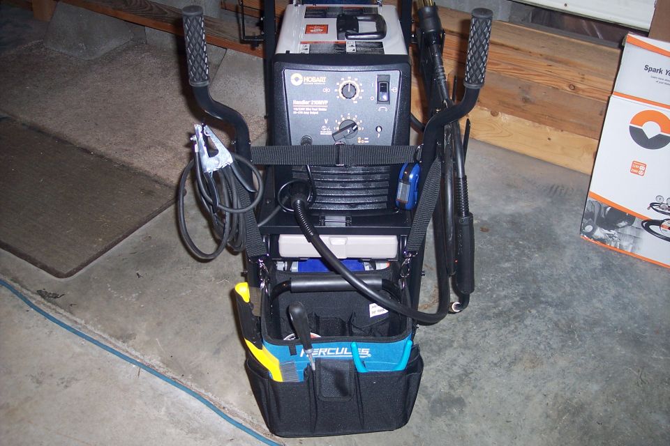 Hobart welding machine on a cart with tools in a bag.