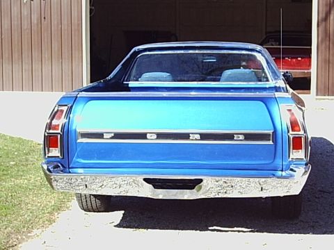 2000 Ford Taurus - Rear view of a blue Ford pickup truck parked in front of a garage, with another red vehicle visible inside.