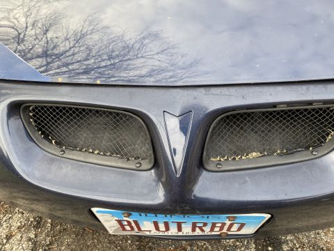 Close-up of a dark blue Pontiac Grand Prix front grille and license plate.