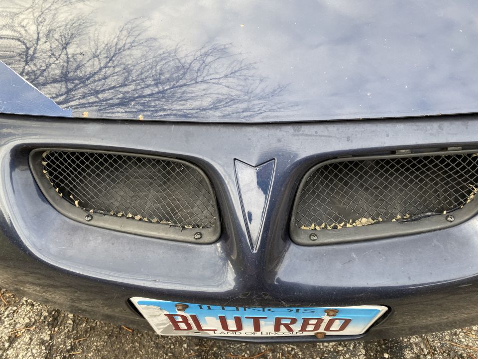 Close-up of a dark blue Pontiac Grand Prix front grille and license plate.