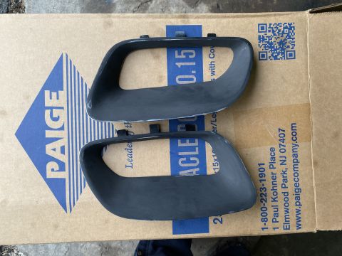 Two dark gray automotive trim pieces on a cardboard box.